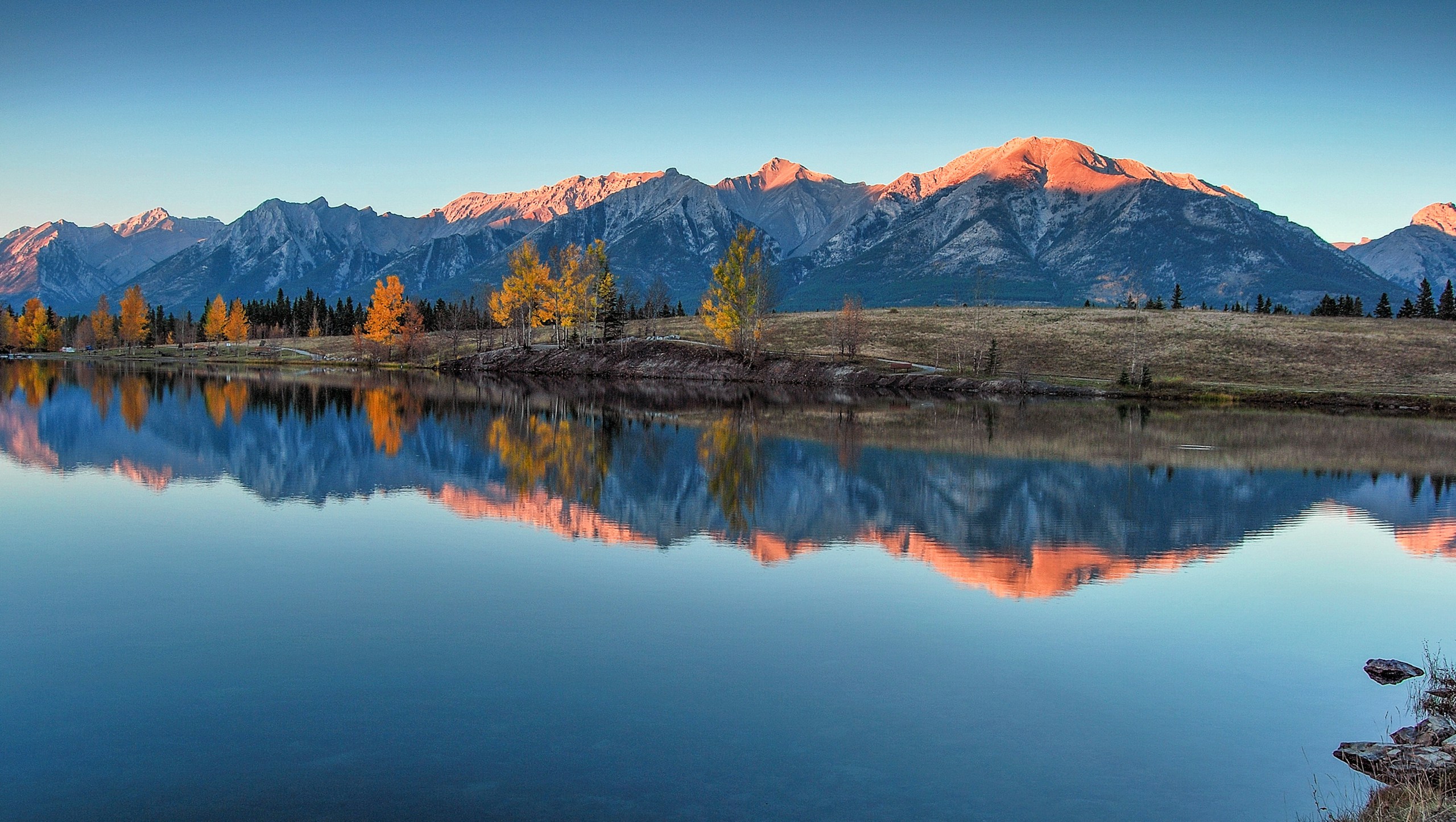 a mountain range is reflected in the still water of a lake