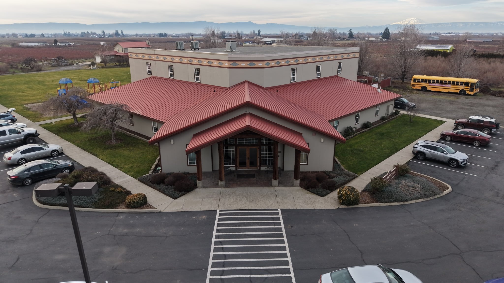 Front view of All Nations Center with its entrance, decorative facade, and a mountain in the distance