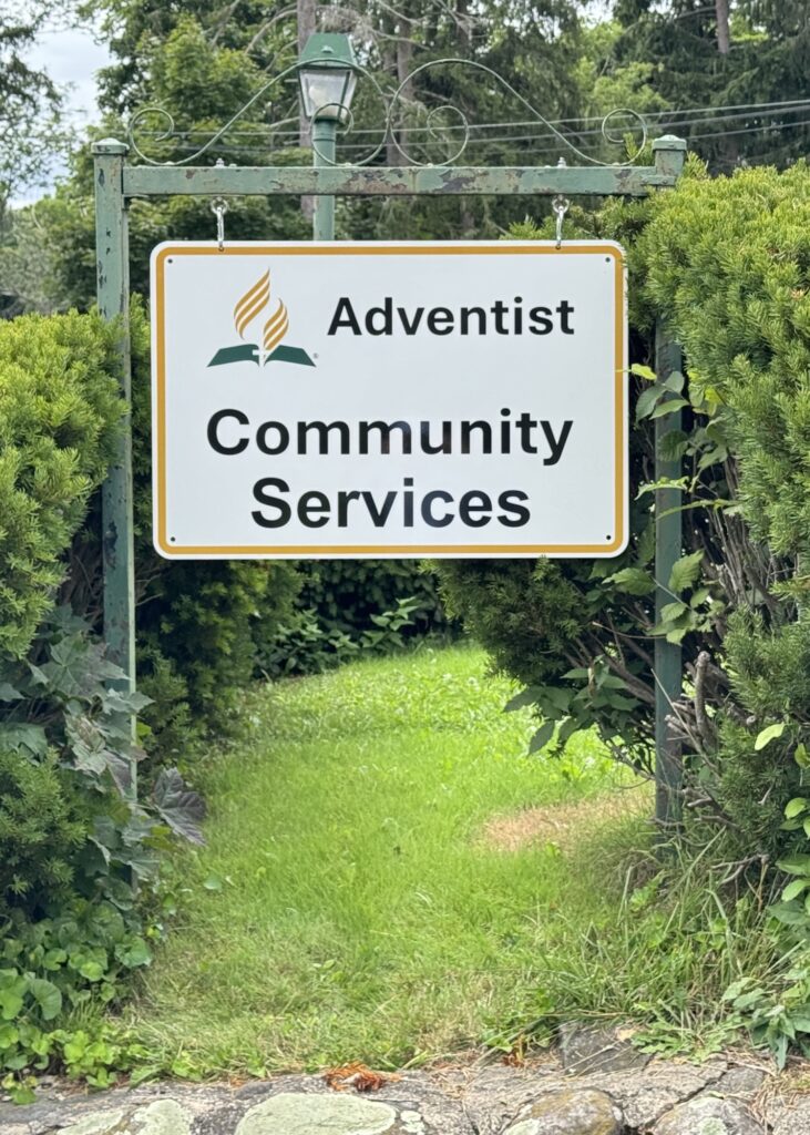 Adventist Community Services sign over a garden path