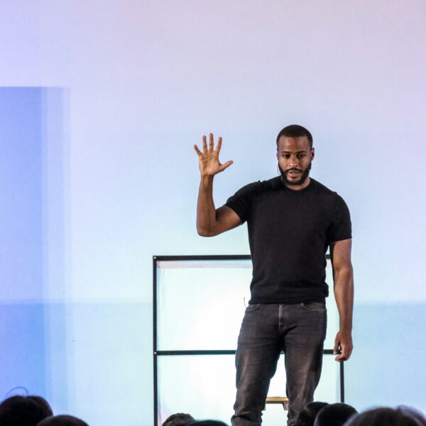 A man standing on a stage with his hands in the air