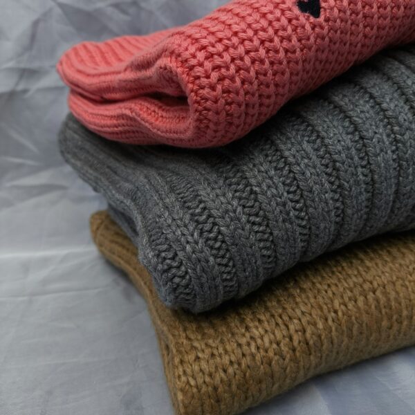 A stack of three knitted sweaters sitting on top of each other