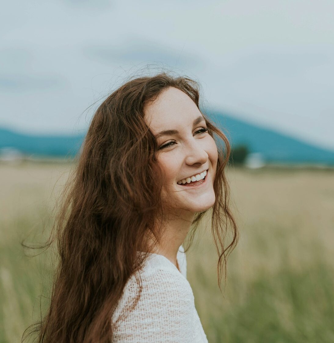 woman smiling white standing on green grass field during daytime