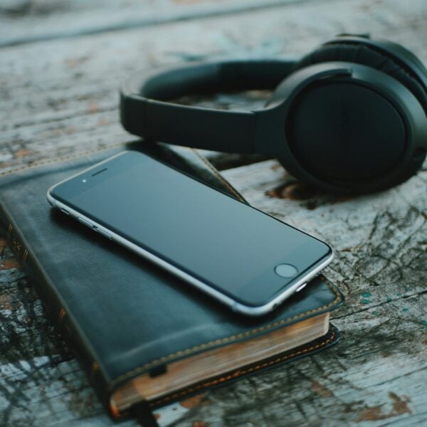 space gray iPhone 6 on book near black wireless headphones