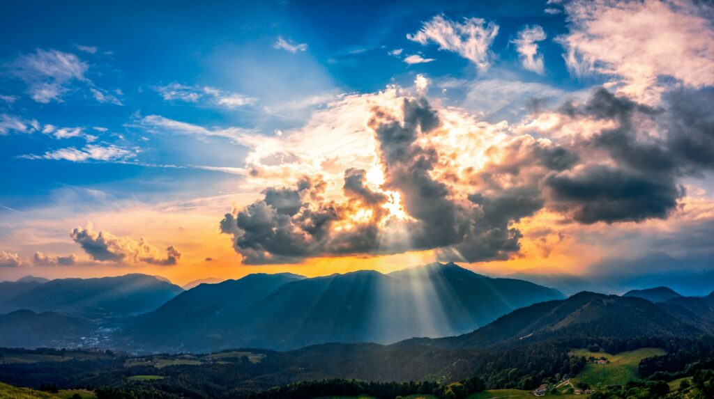 the sun is shining through the clouds over the mountains