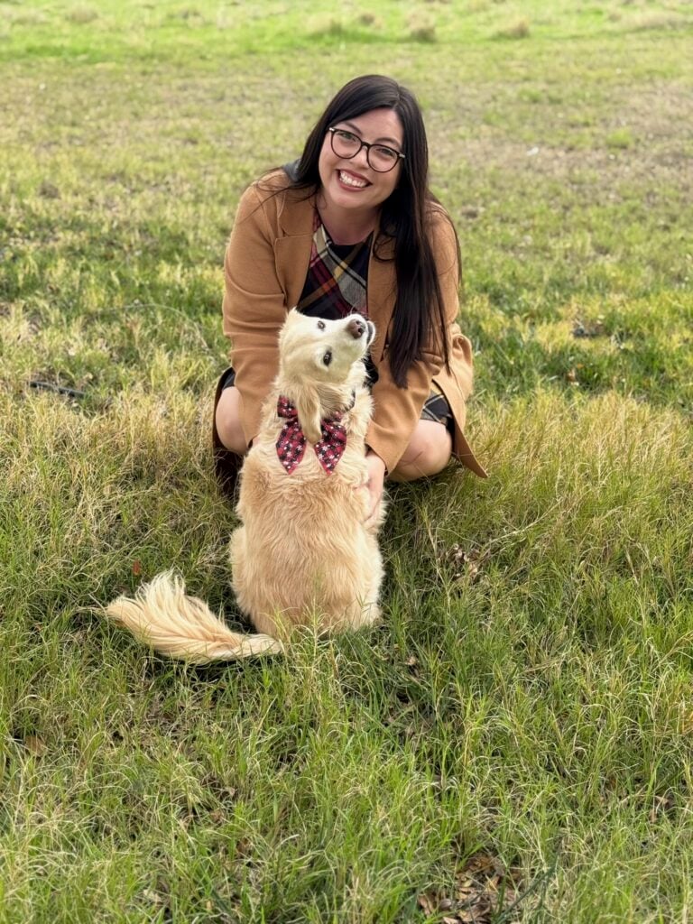 A BAA teacher sitting in the grass with her golden retriever