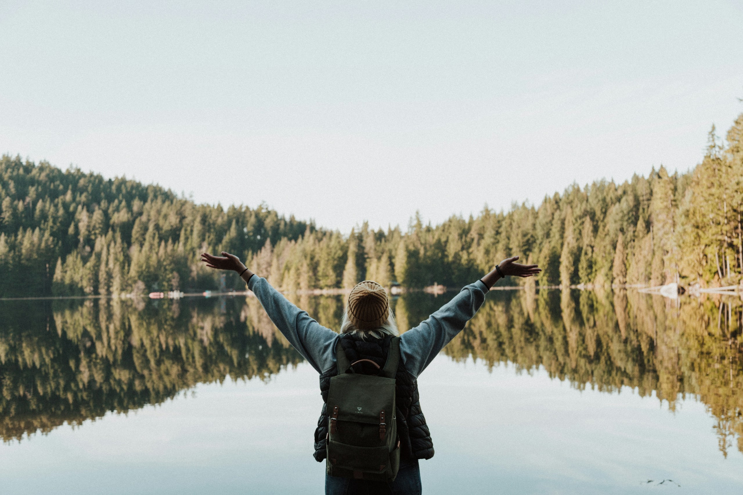 woman open her arms facing calm body of water