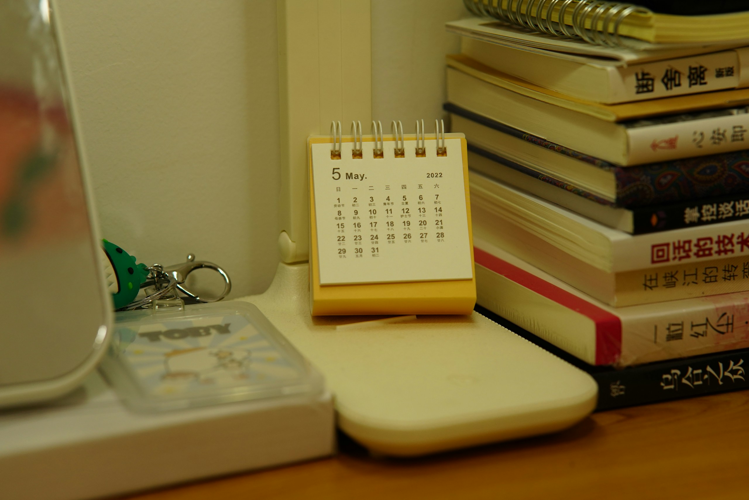 A small desk calendar sits beside a stack of books.