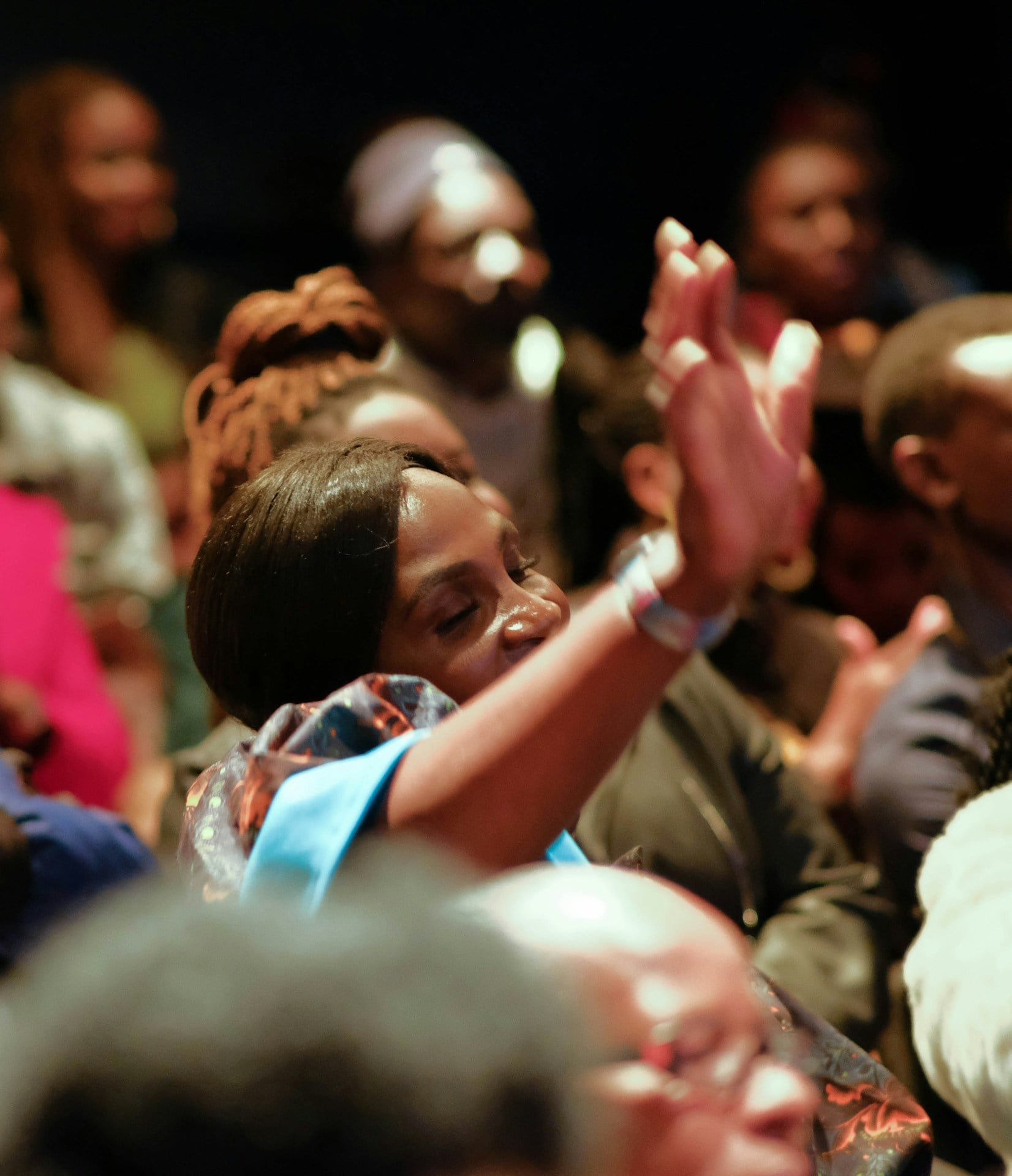a group of people sitting in a room with their hands up