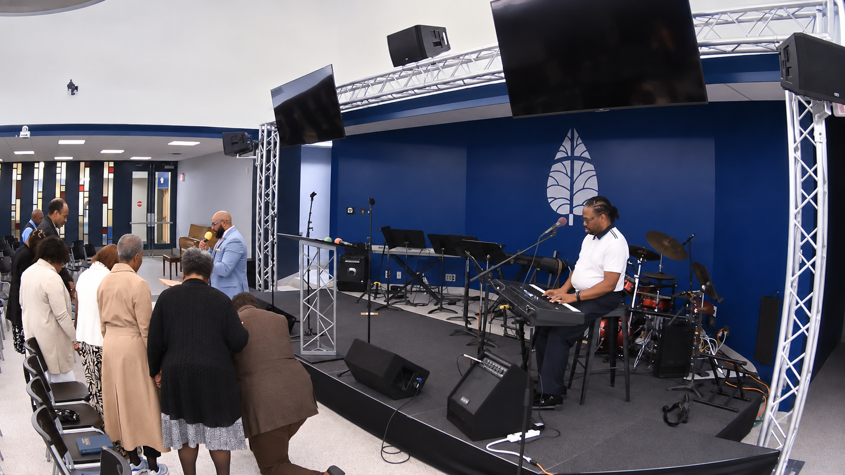 Congregants bow their heads near a keyboard musician during a prayer gathering.