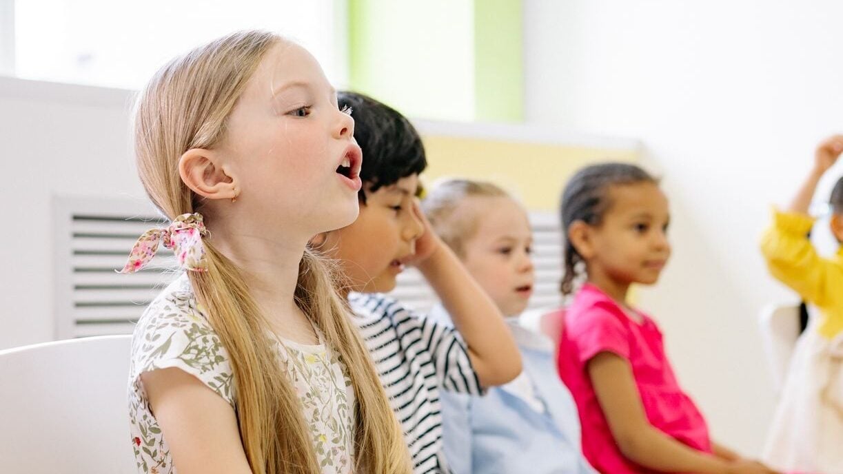 Young children of diverse backgrounds engaging in a fun classroom activity, seated together inside a bright room.