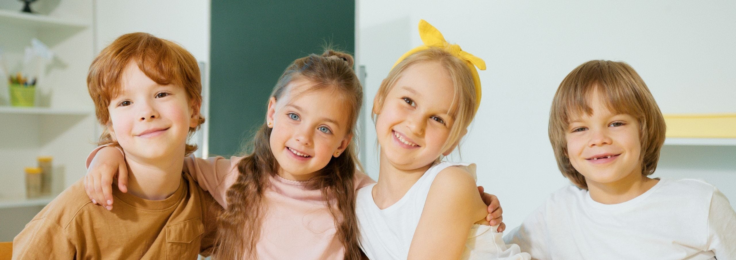Happy group of children smiling and posing together in a bright classroom setting.