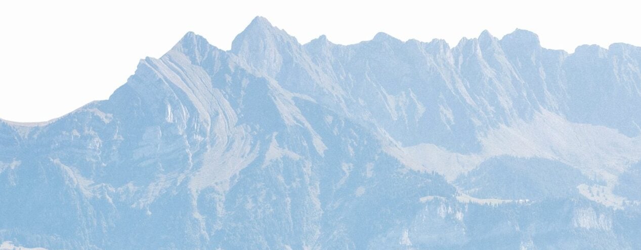 Hotel nestled by a serene lake with mountains behind