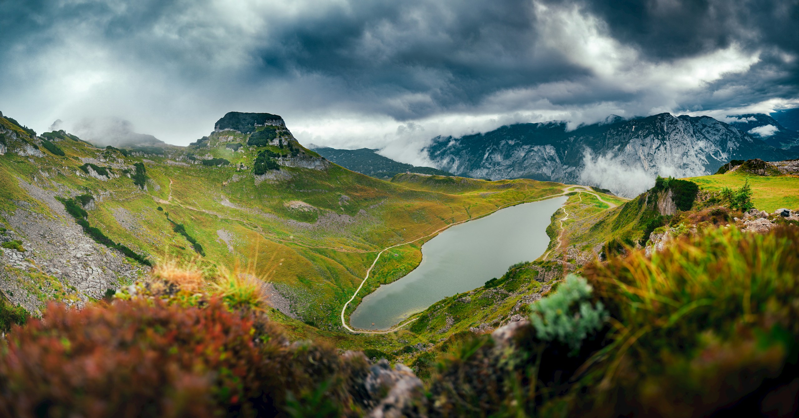 Dramatic mountain landscape with a lake and stormy sky.