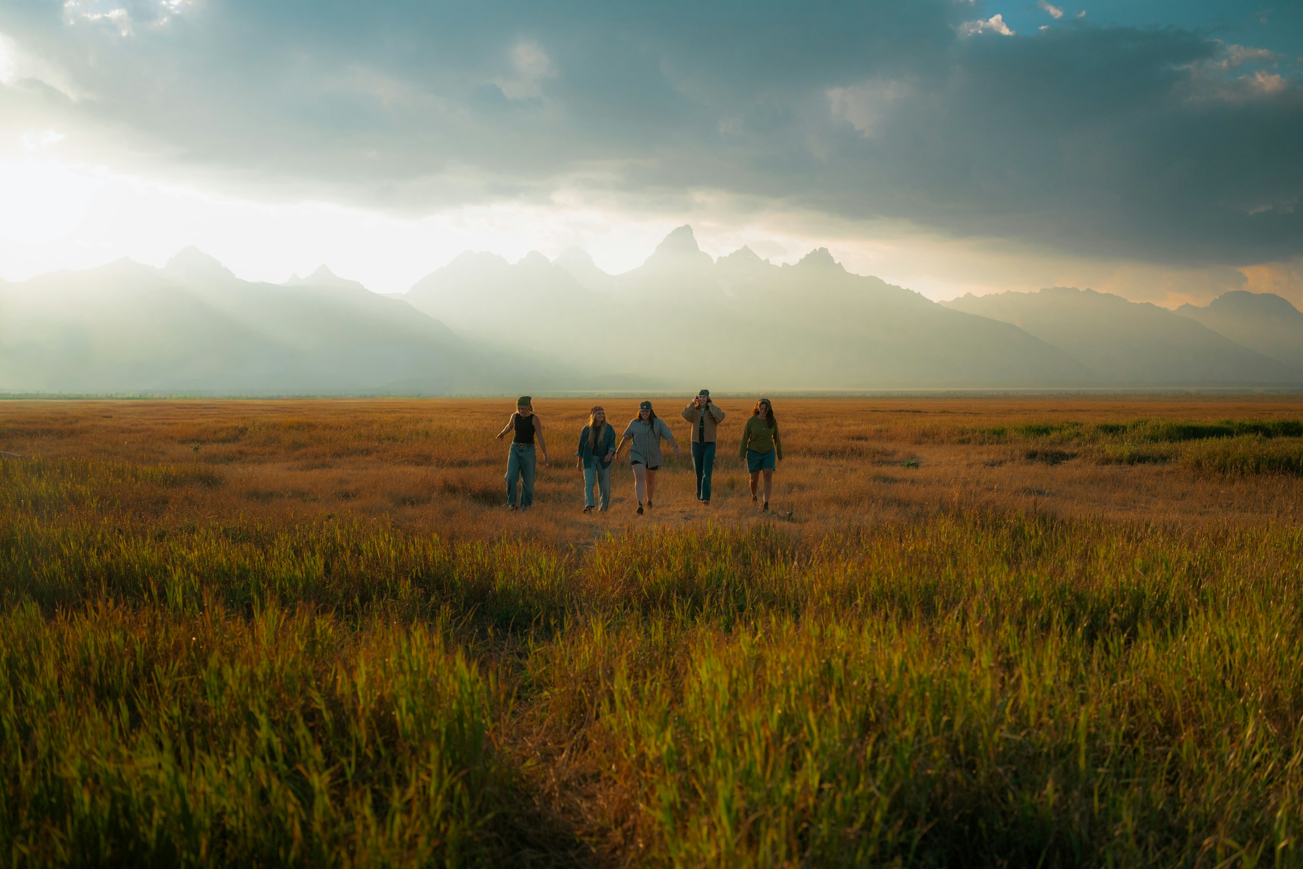 Group walking through a grassy field toward mountains