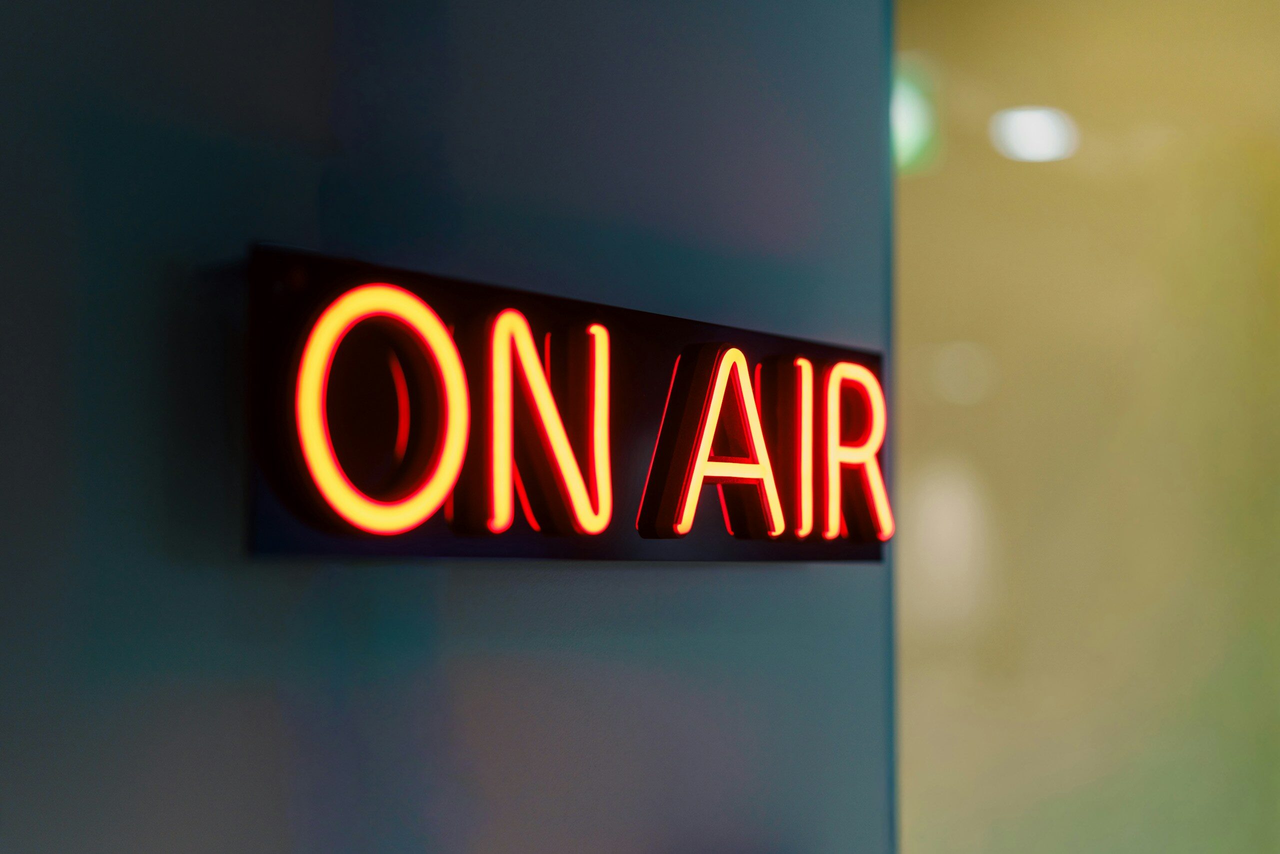 Red neon "on air" sign glowing on wall