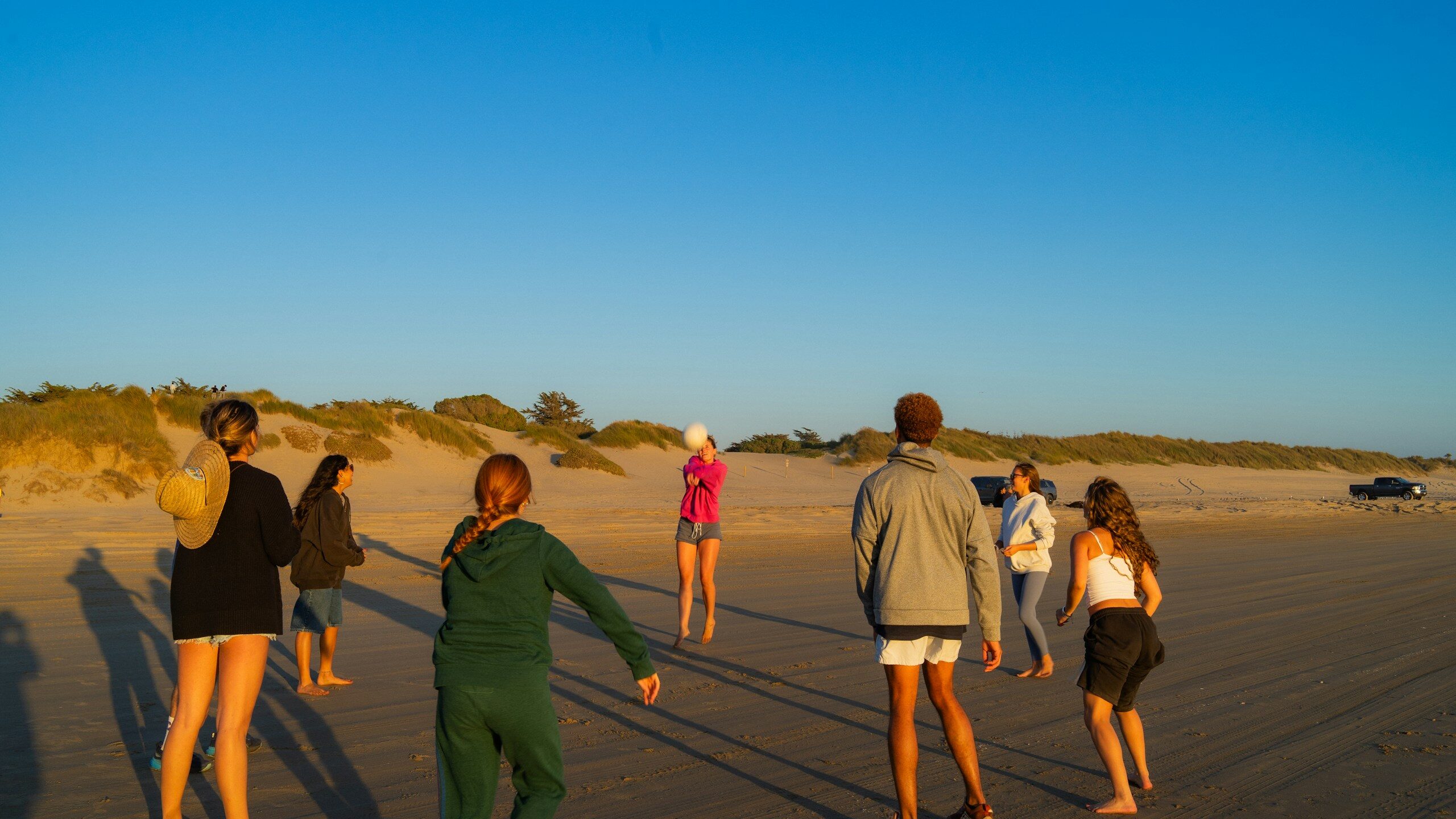 Group of friends playing on a sandy beach at sunset