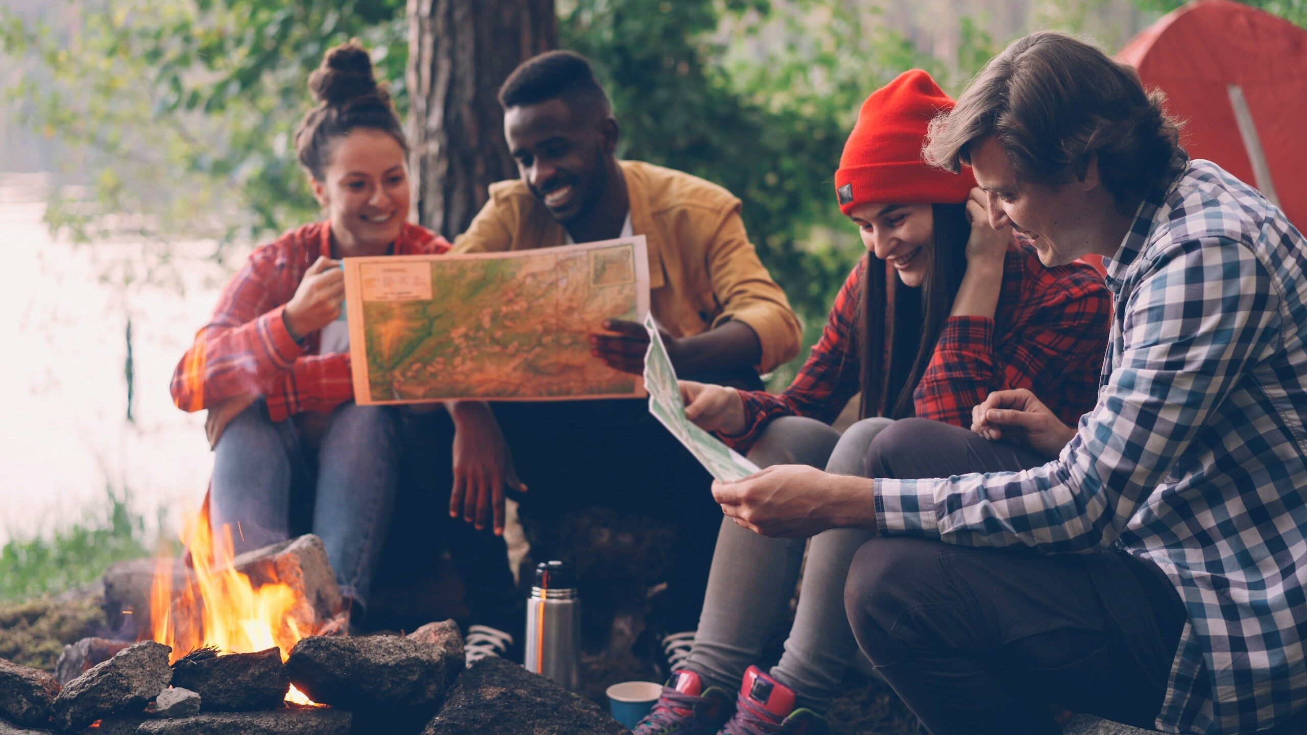 Group of friends looking at map by campfire