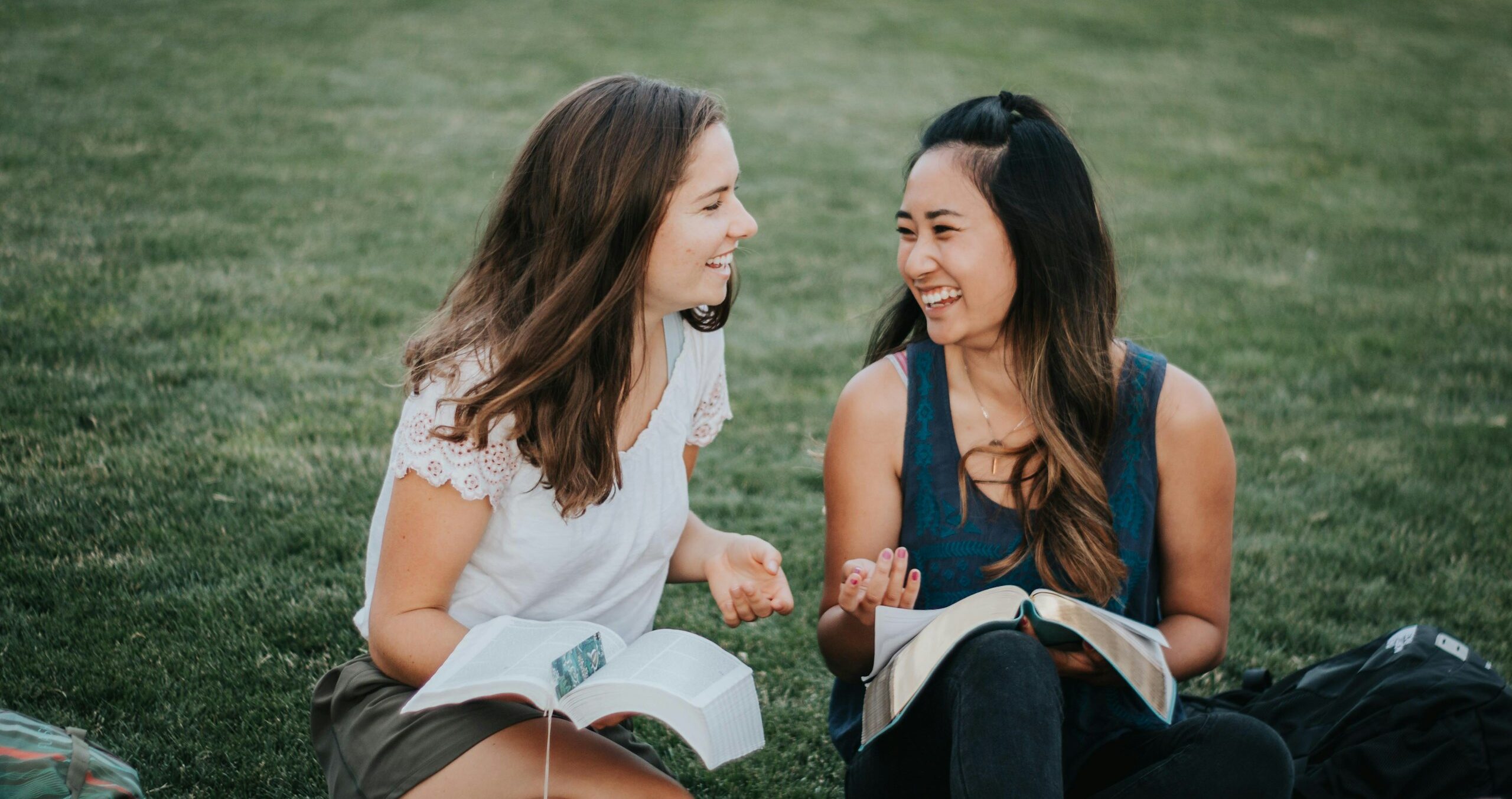 a couple of women sitting on the grass
