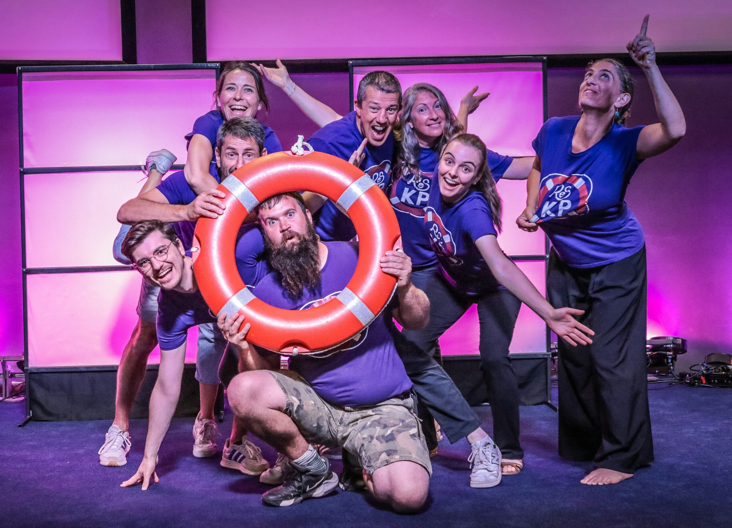 A playful group of people posing with a red lifebuoy