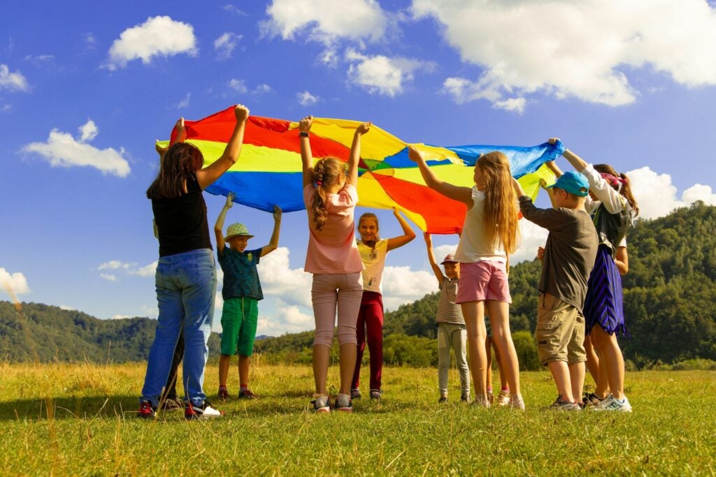 children playing with colorful parachute on grass