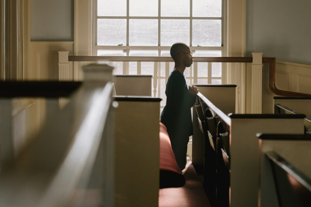 A person kneels inside of a church.