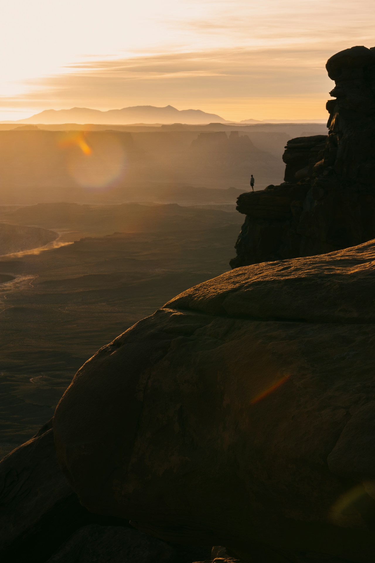 Silhouette of a person on a cliff at sunset