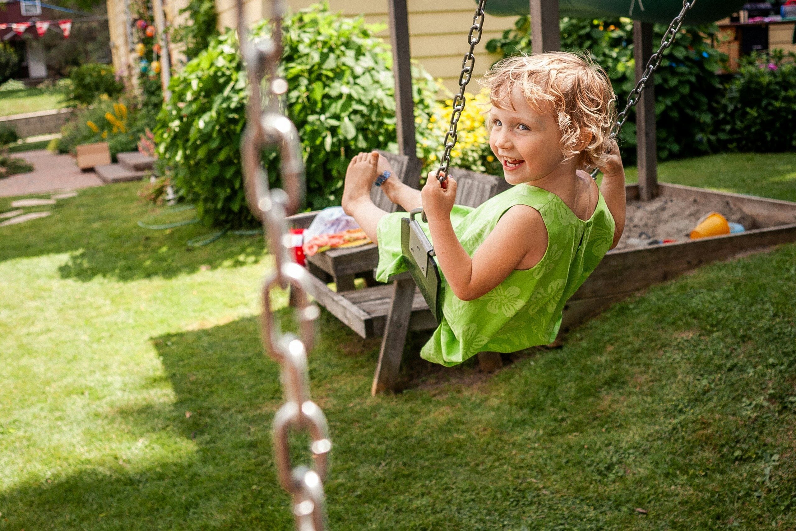 A young girl smiles while swinging on a porch swing.