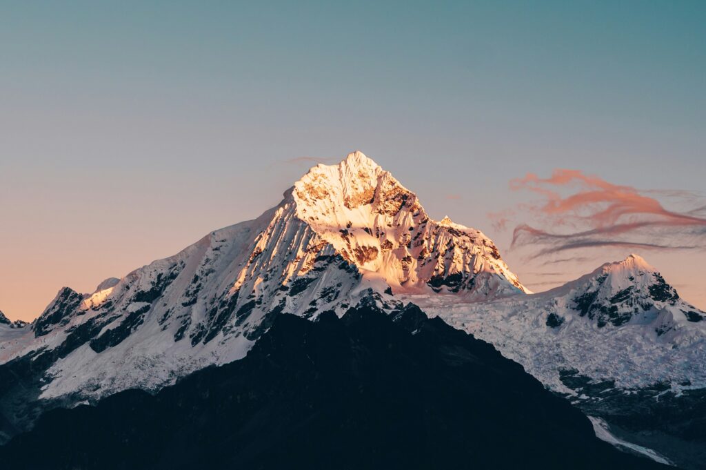 Snow-capped mountain peaks glow at sunrise.