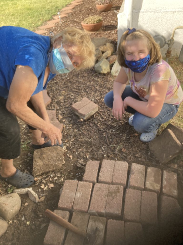 Mrs. Riddlesperger and Abi make a brick path together.