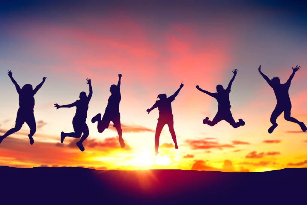Silhouette happy friends jump on sunrise sky at top of mountain
