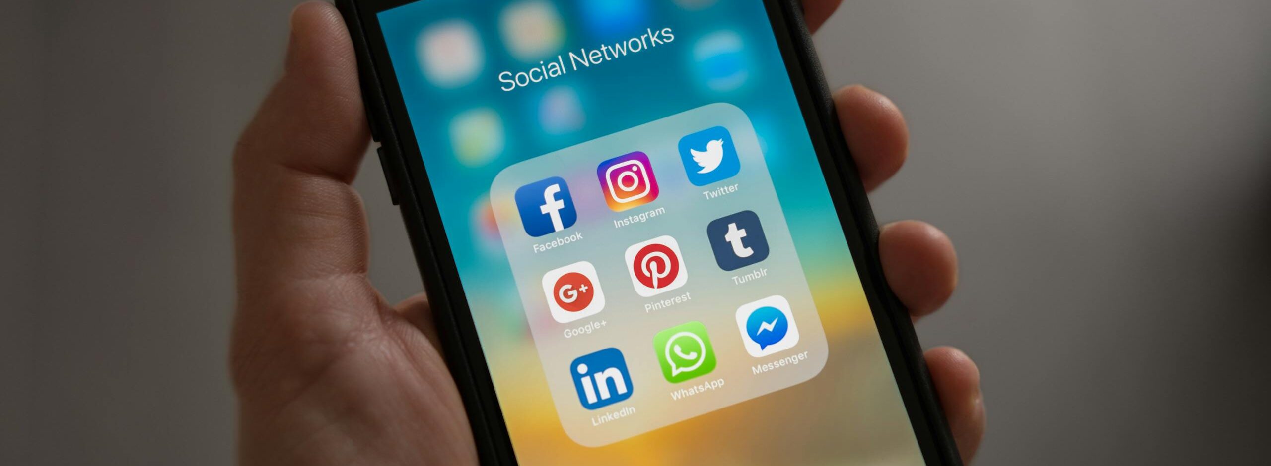 A smartphone displaying various social media icons held in a hand, showcasing modern communication apps.
