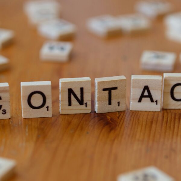 A wooden table topped with scrabble tiles spelling contact