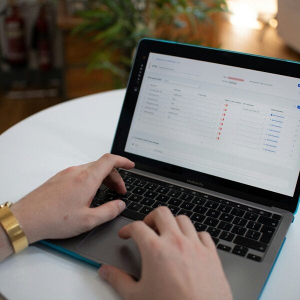 Hands typing on a laptop with a spreadsheet on screen.