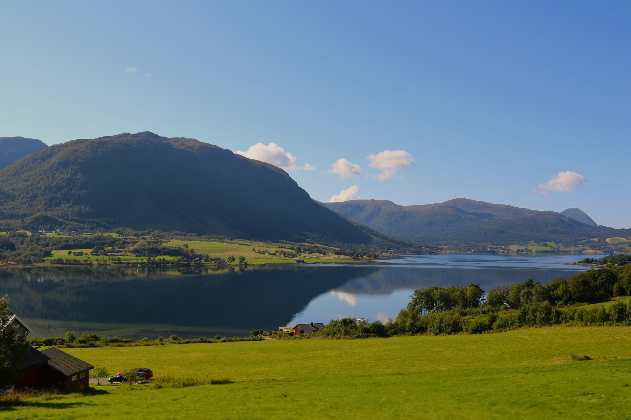 A grassy field with a lake and mountains in the background