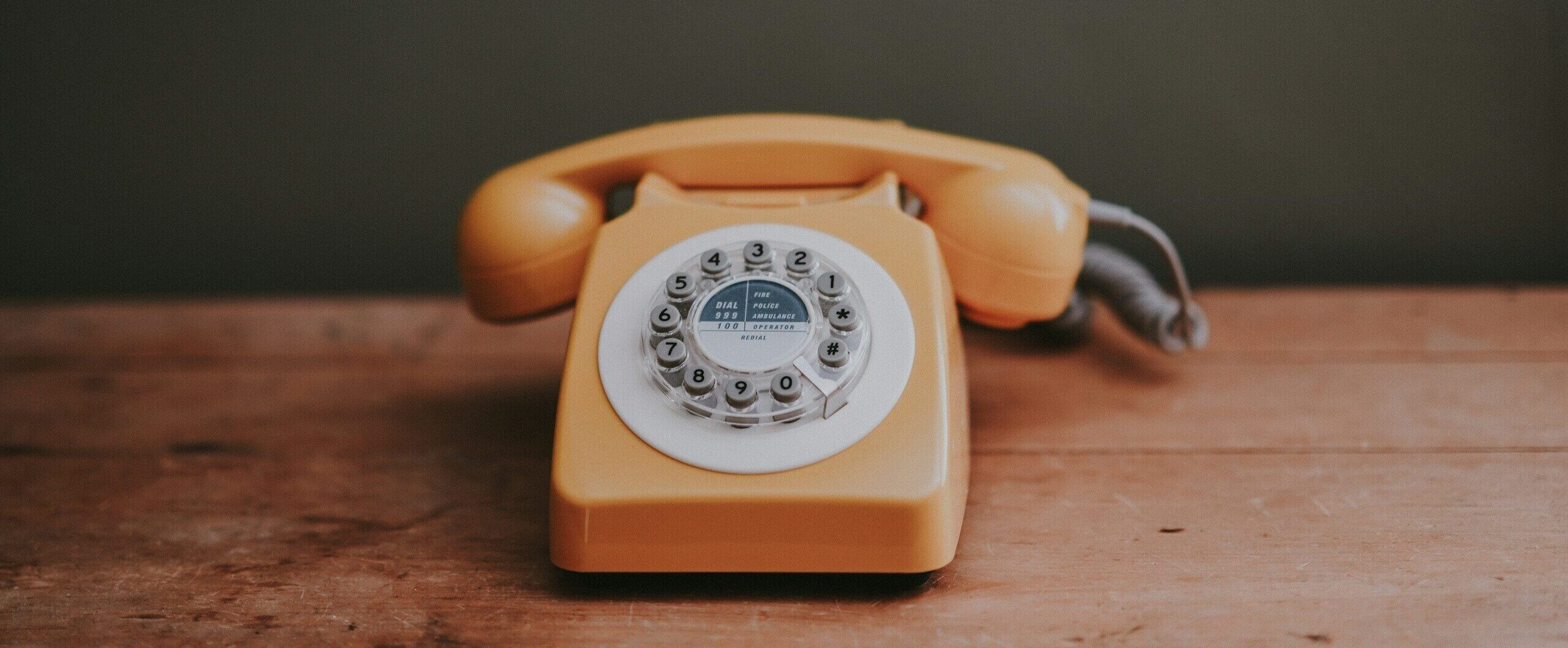 brown rotary dial telephone in gray painted room