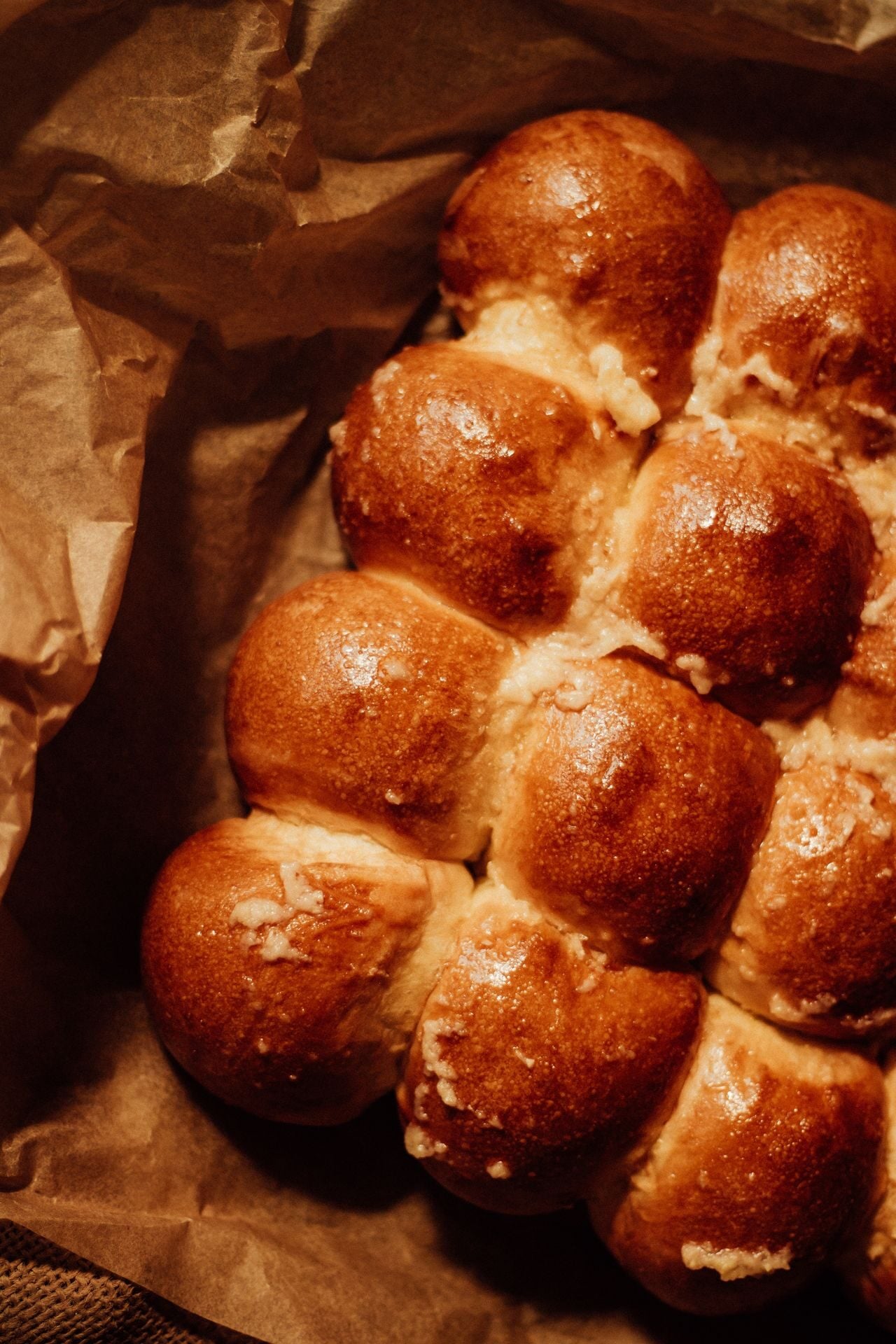 Close-up of freshly baked bread rolls with a golden brown crust on parchment paper, showcasing homemade craftsmanship.