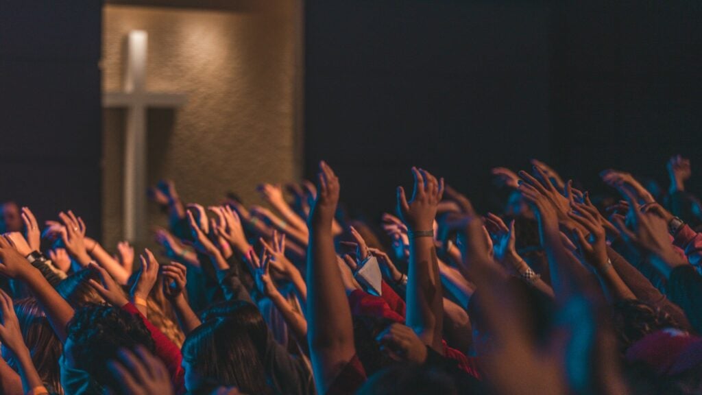 people raising their hands in front of stage