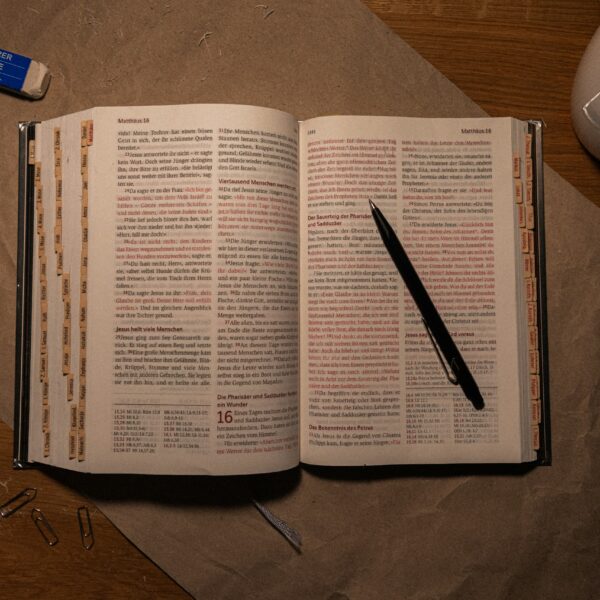 An open book on a table with a pen and pencil
