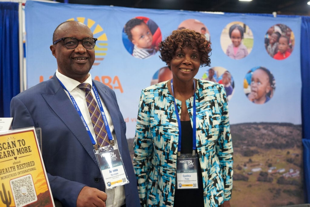 Jerome Habimana and Cynthia Prime stand together in front of the SOHO booth at the ASI International exhibit hall.