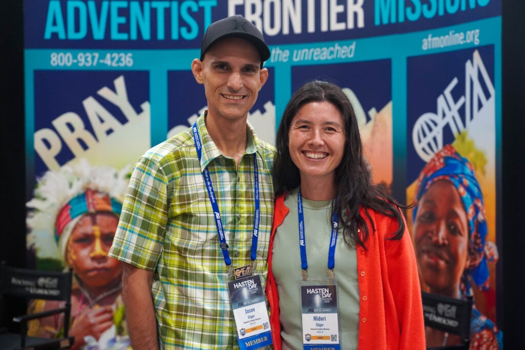 Jason and Midori Sliger stand behind their Adventist Frontier Missions booth in the ASI International 2026 exhibit hall.