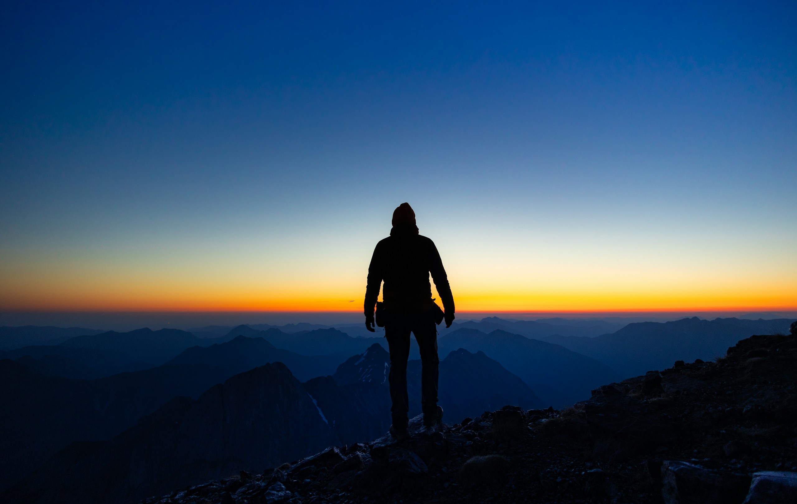 A person admiring the sunset over mountains.