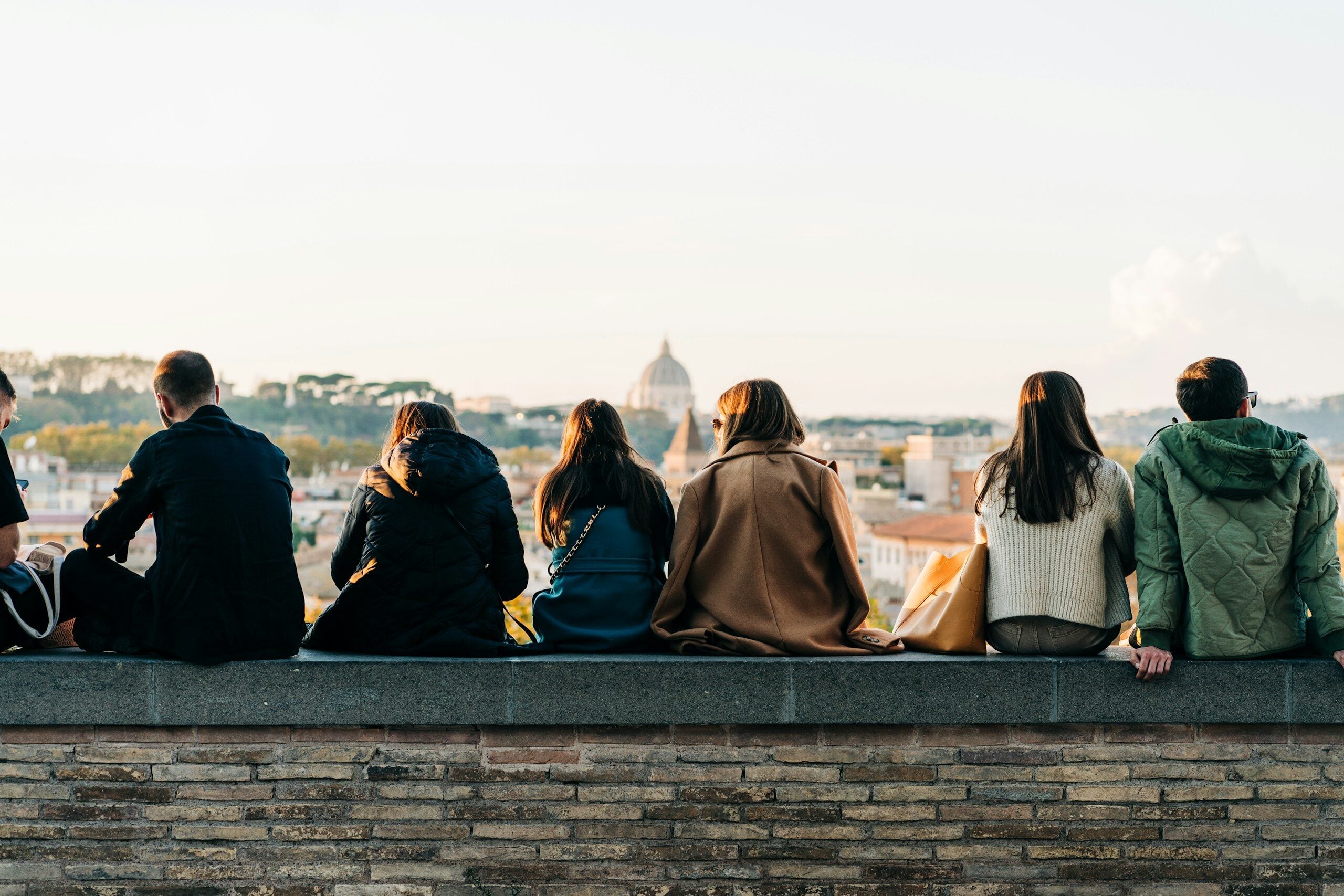 a group of people sitting on top of a brick wall