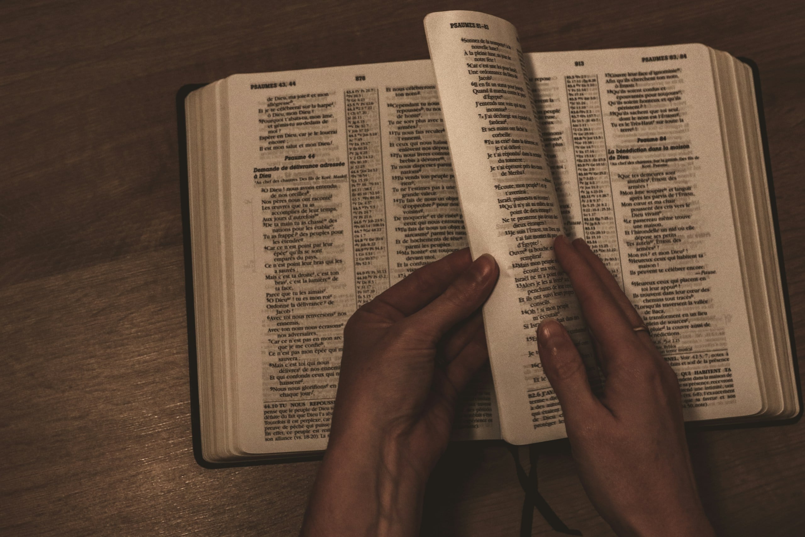 person holding turning pages in a Bible