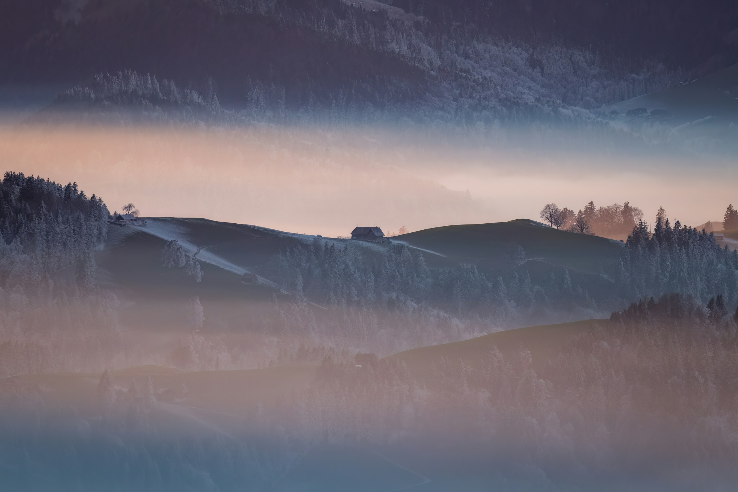 Misty hills with a small cabin at sunrise.