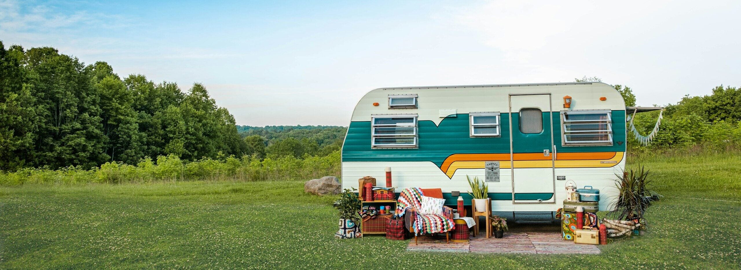 white and blue rv trailer on green grass field under blue sky during daytime