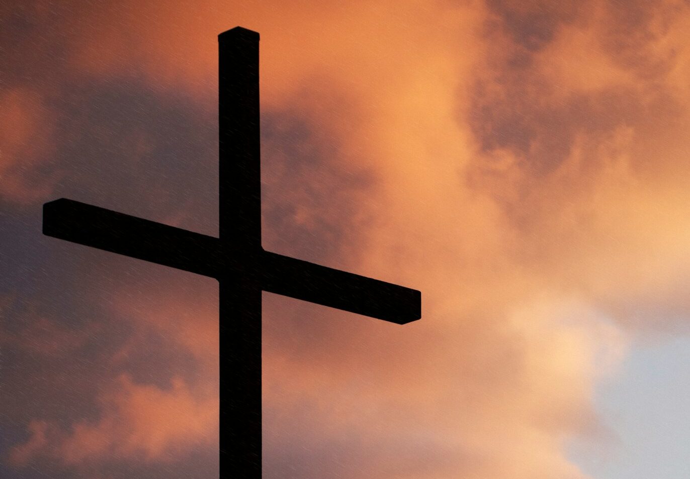 silhouette of large cross under orange sky