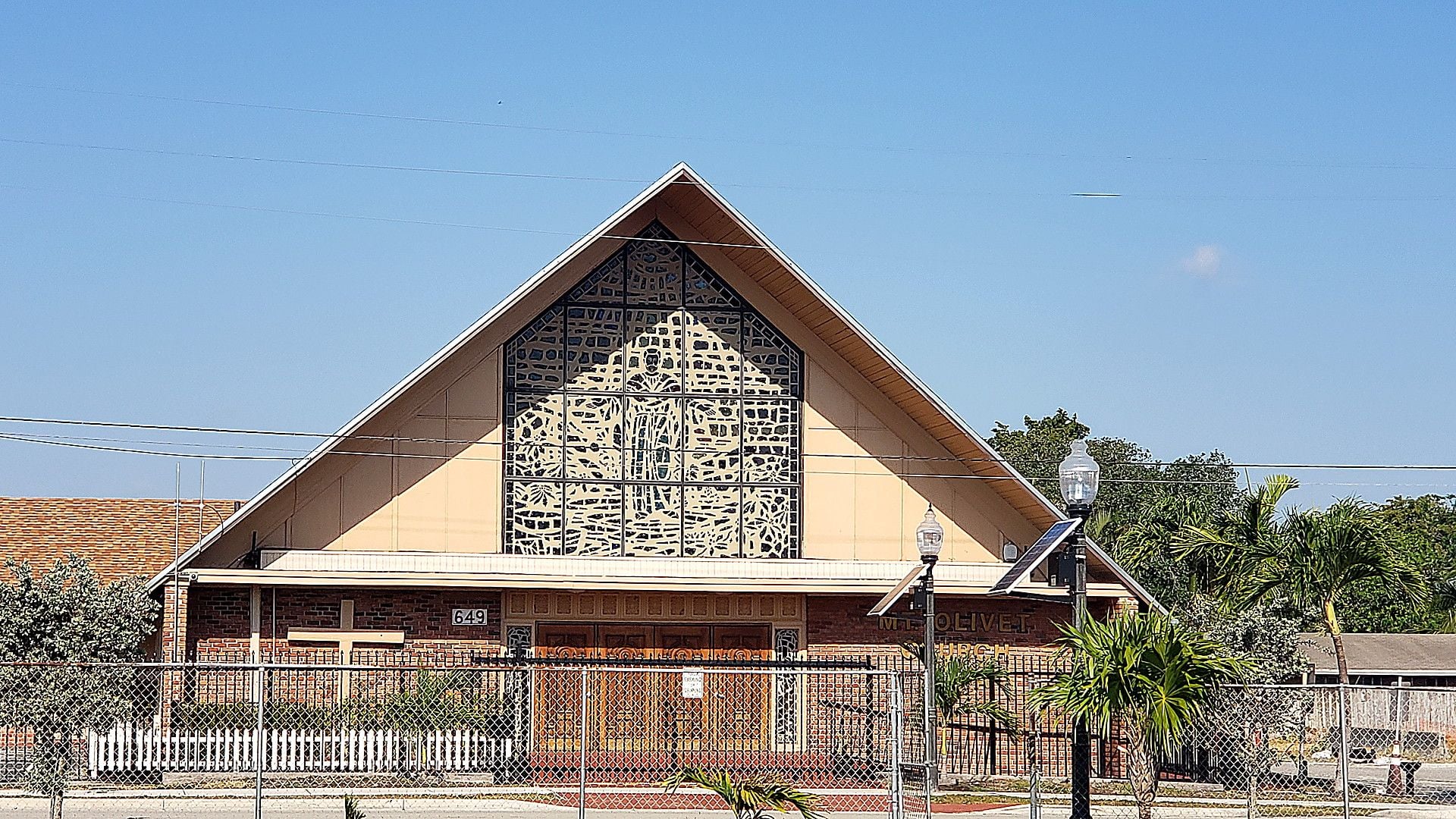 Mount Olivet Seventh-day Adventist Church in Fort Lauderdale, a brick building with a steep A-frame roof and a large stained-glass window above the entrance