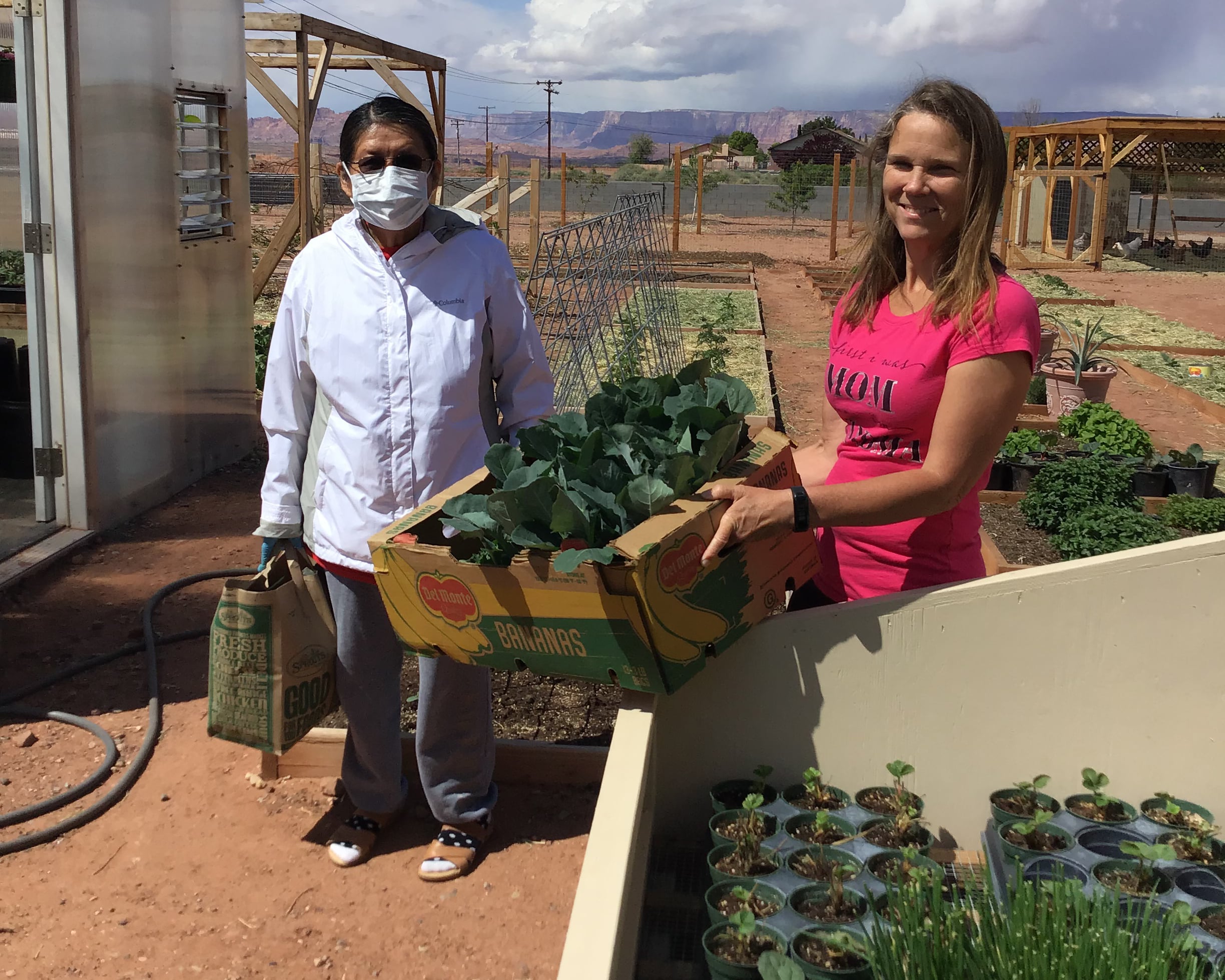 Nancy Crosby (R) assists a community member with a box of fresh produce.