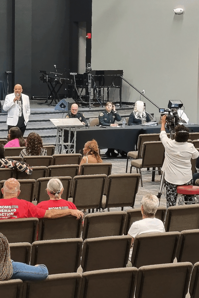 Black man stands in front of a crowd in an auditorium, speaking