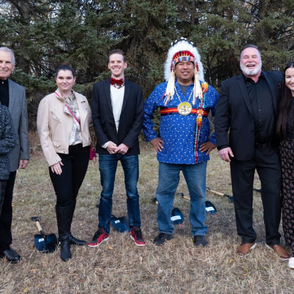 Several people standing on a patch of grass, including an Indigenous chief in costume.